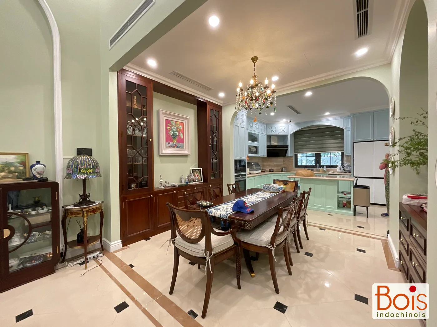 Ảnh thực tế — Bàn ăn, hệ tủ trang trí và bếp được nhìn trong cùng một mạch không gian.